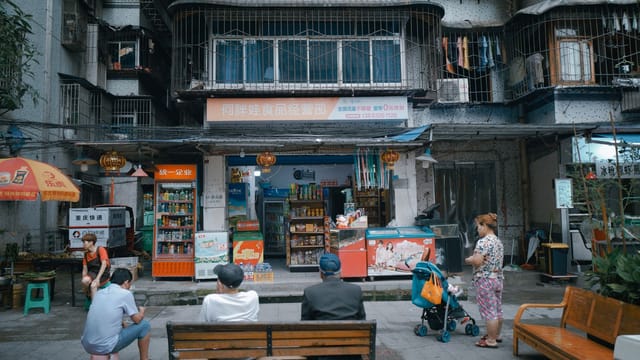 Outdoor view of a bustling Asian grocery store and street activity.