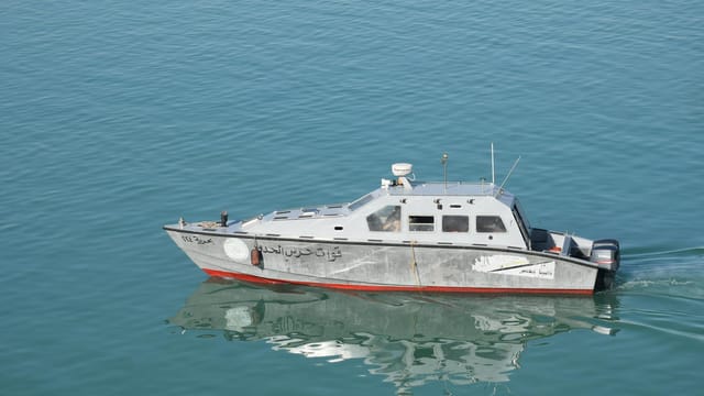 Navy patrol boat cruising on serene waters in Egypt, reflecting on the sea's surface.