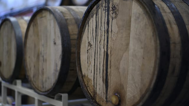 Close-up of wooden wine barrels used for fermentation and storage in a winery cellar.