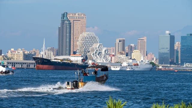 A cityscape of Kaohsiung Harbor showcasing iconic geometric architecture and bustling maritime activity.