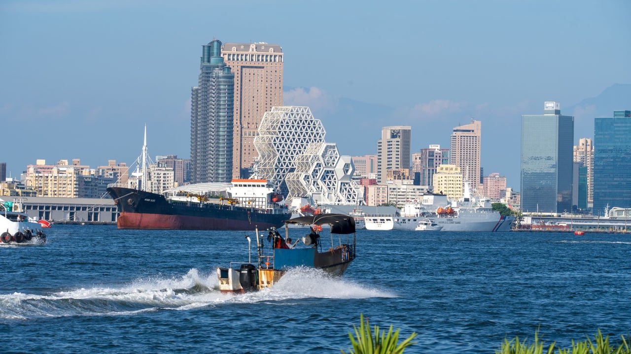 A cityscape of Kaohsiung Harbor showcasing iconic geometric architecture and bustling maritime activity.