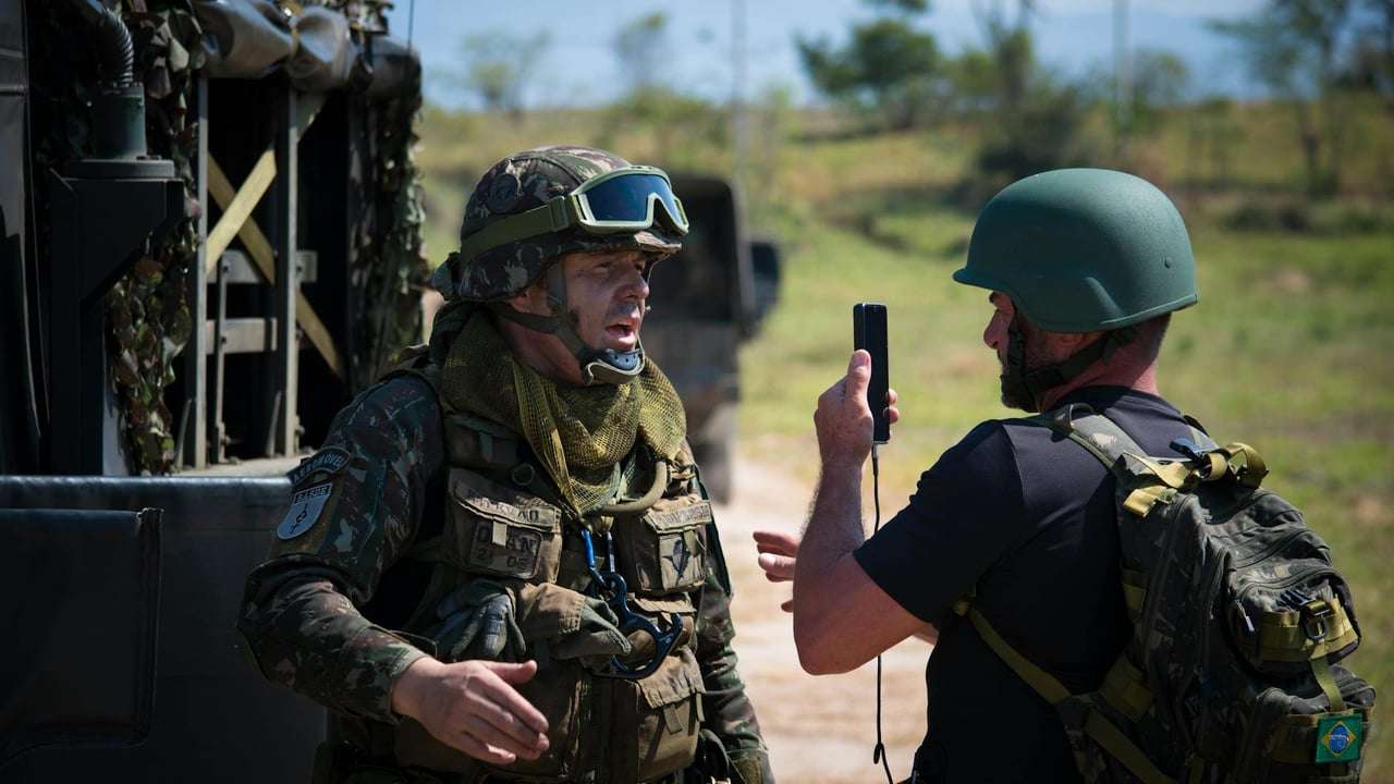 Two soldiers in full gear having a tactical discussion outdoors beside military vehicles.