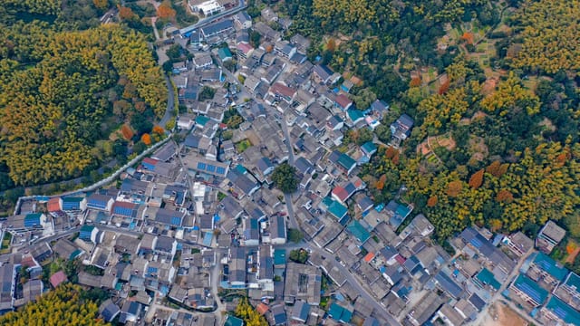 Aerial photograph of a residential neighborhood surrounded by lush greenery in Shaoxing, China.
