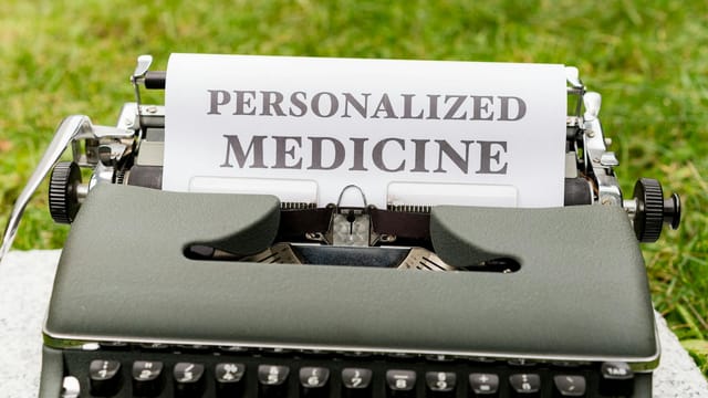 A vintage typewriter outdoors displaying a paper with the text 'Personalized Medicine'.