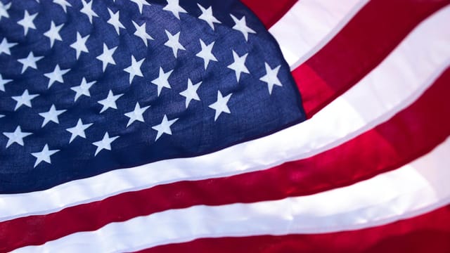 A detailed, soft-focus close-up of the American flag showcasing stars and stripes in vibrant colors.