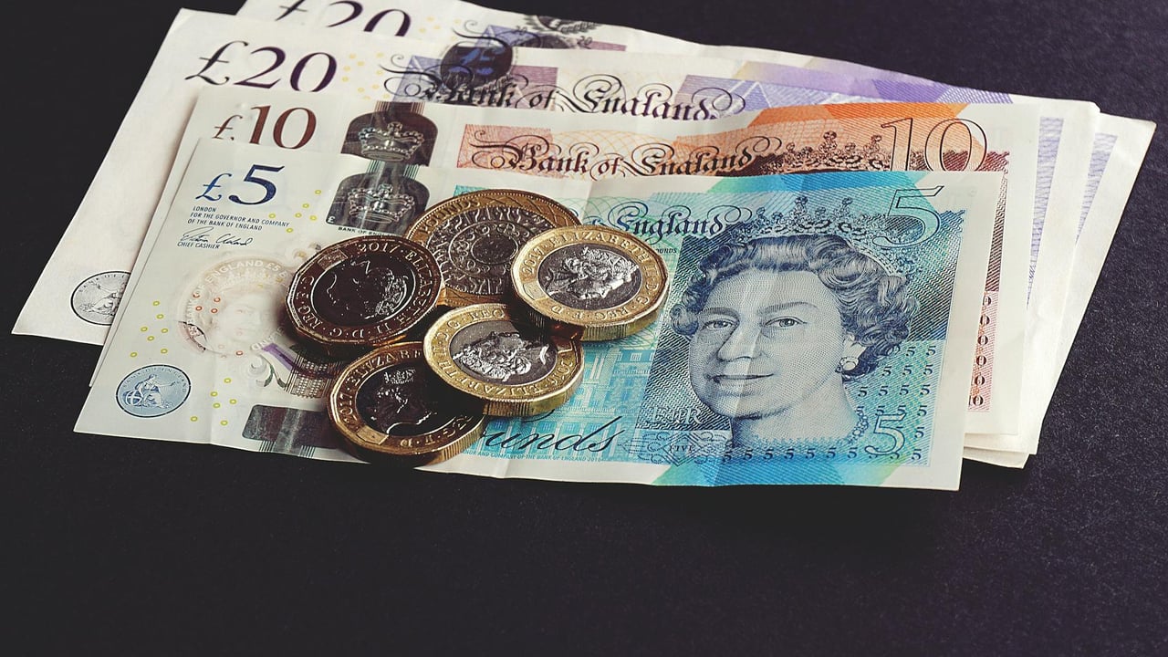 High-quality image of British pound notes and coins on a dark surface, showcasing currency detail.