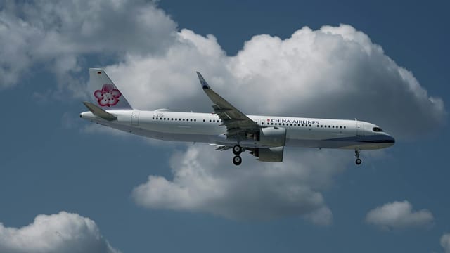 A China Airlines aircraft captured flying over Hamburg with a clear blue sky backdrop.