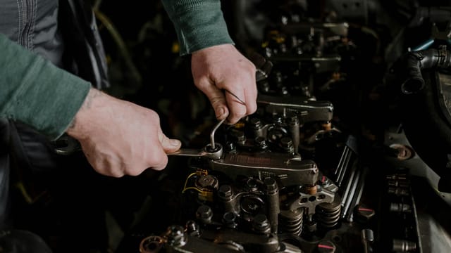 Close-up of a mechanic using hand tools to fix an engine, showcasing precision and skill.