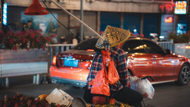 A vibrant scene of a street vendor on a bicycle at a night market in Guilin, China.