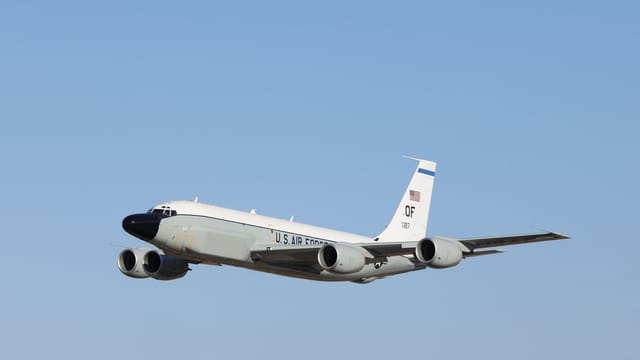 A U.S. Air Force jet flies high in a clear blue sky, showcasing powerful military aviation.