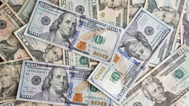A close-up view of scattered US dollar bills showcasing various denominations and presidents.