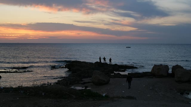 People fishing at sunset on the Mediterranean coast in Tyre, Lebanon.