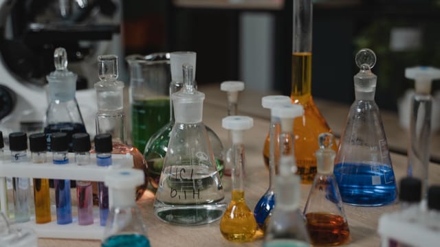 Various colored chemical liquids in glassware on laboratory table, perfect for scientific visuals.
