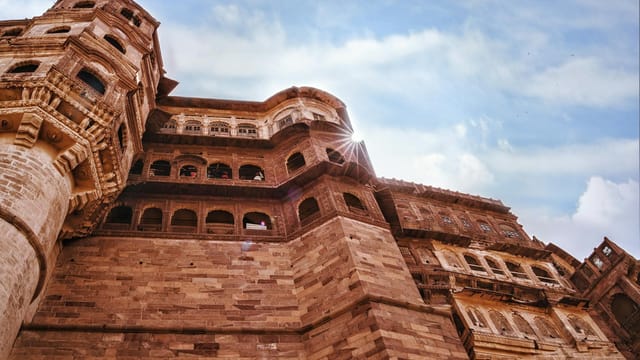 Low angle view of the historic Mehrangarh Fort with sunlit stone architecture.