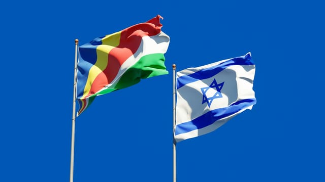 Seychelles and Israel flags waving against a clear blue sky, symbolizing international unity.