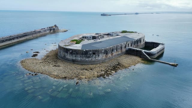 Aerial shot of a historic fort on an island surrounded by the ocean.