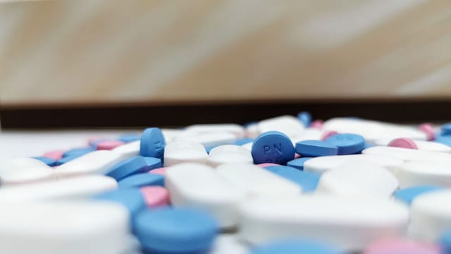 Close-up image of assorted blue and white pills scattered on a table, indoors.