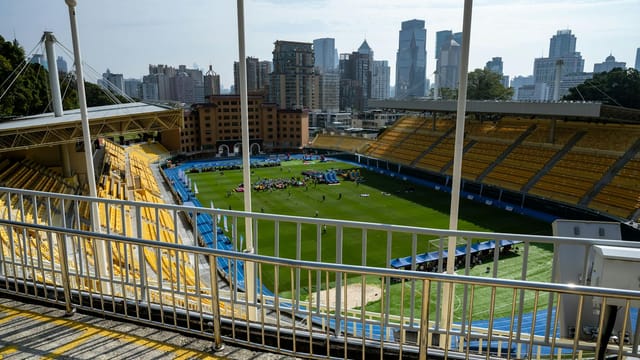 Wide-angle view of a Guangzhou sports stadium with city skyscrapers in the background.