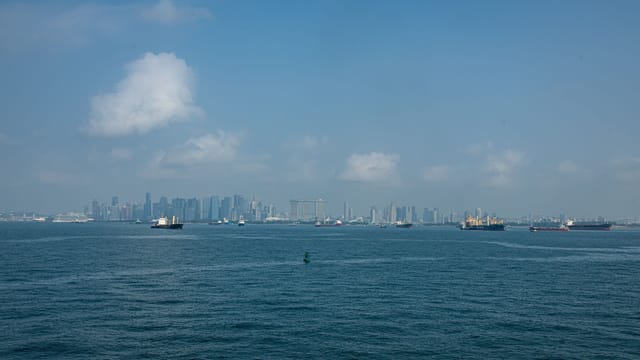 View of Singapore skyline with vessels navigating the sea under a clear blue sky.