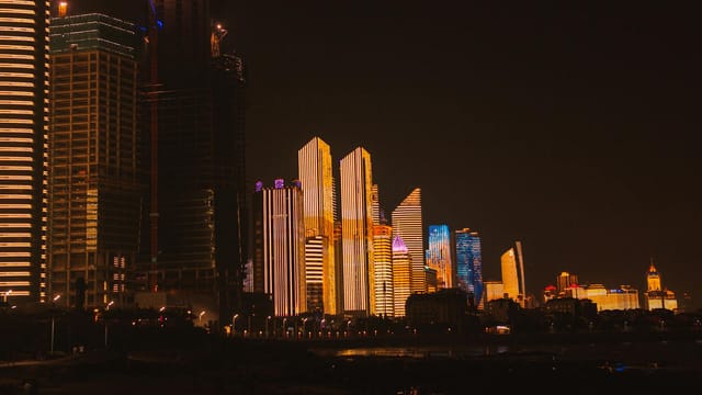 Illuminated lights of skyscrapers located in modern city district under dark night sky