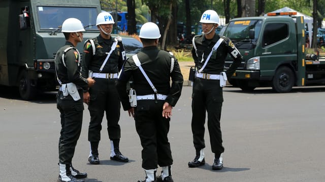 Group of military policemen in uniform standing on a city street.