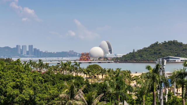Scenic view of Zhuhai city skyline with lush greenery and iconic opera house.