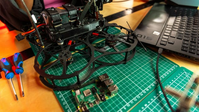 Drone assembly on a desk with laptop and tools, capturing modern tech.