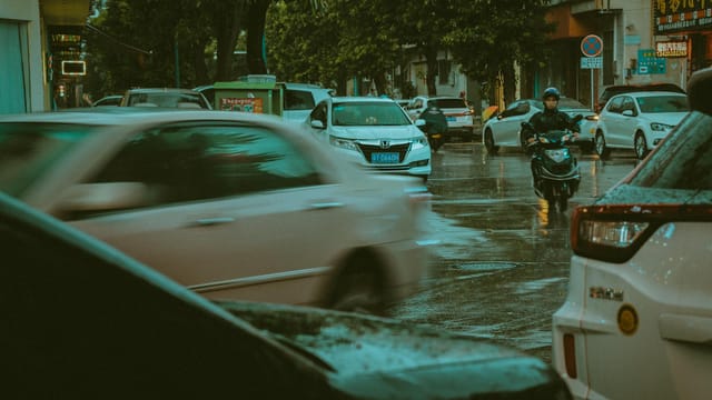 Dynamic scene of rainy day traffic in a Chinese city, highlighting motion and energy.