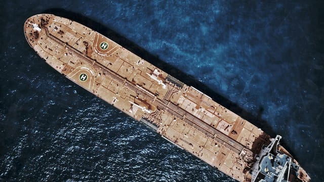 Drone shot of large tanker ship with helipads in ocean waters.