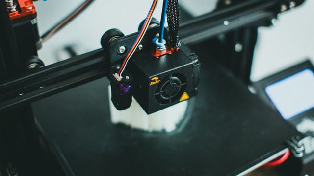 Detailed shot of a 3D printer creating an object, focusing on the cooling fan and print head.