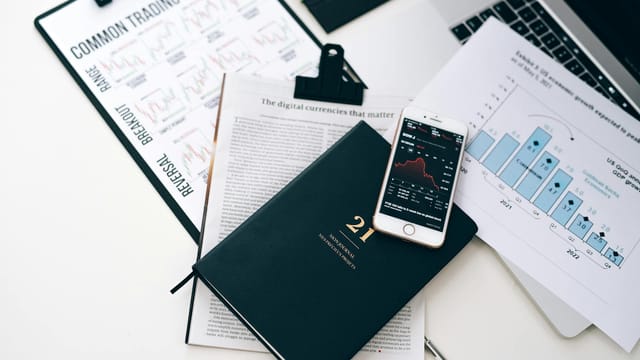 High-angle shot of a stock trading desk with charts, graphs, and a smartphone displaying market trends.