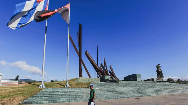 Wide view of Revolution Square in Santiago de Cuba, featuring flags and historical monument.