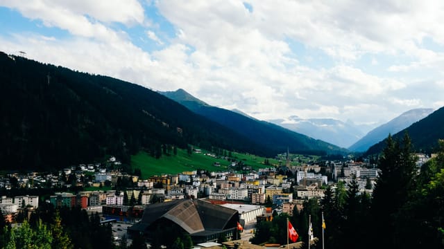 Captivating view of a Swiss town nestled in a lush valley surrounded by majestic mountains.