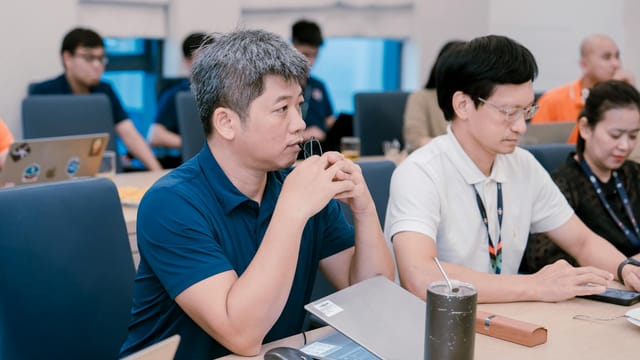 Engaged professionals in a corporate meeting room discussing ideas with laptops and notes.