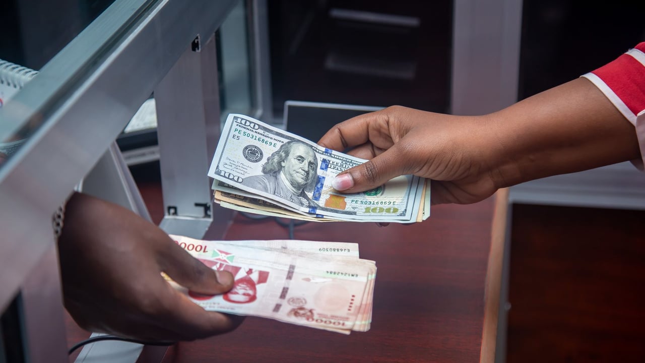 Hands exchanging US and local currency at a bank counter, signifying international finance.