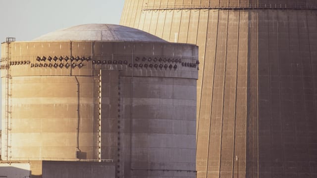 Close-up view of nuclear reactor buildings bathed in golden light, showcasing industrial architecture.