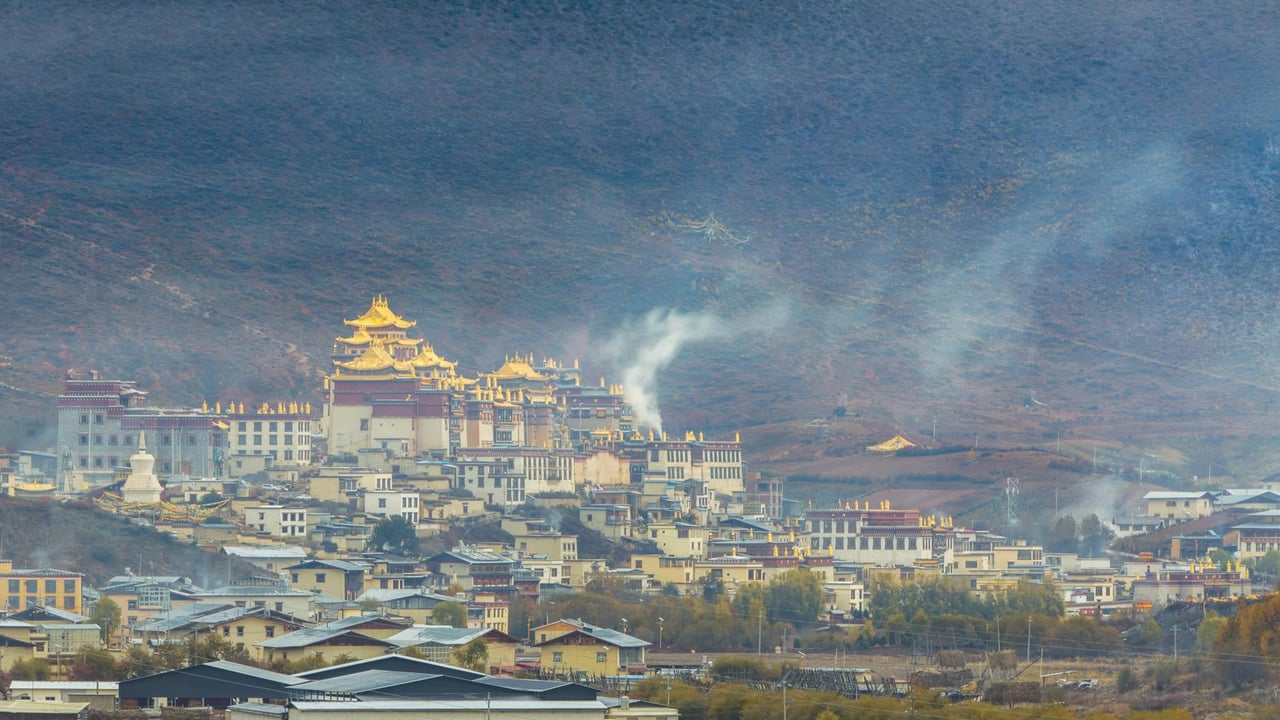 Panoramic view of Shangri-La surrounded by mountains and mist with prominent monastery.