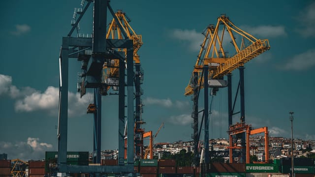 Industrial cranes at the bustling İstanbul port with shipping containers under a clear blue sky.