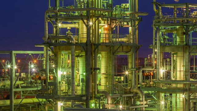 Illuminated industrial gas facility in Dahej, Gujarat, showcasing complex structures under a night sky.