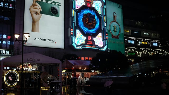 Vibrant urban cityscape at night showcasing illuminated neon billboards and bustling street life.
