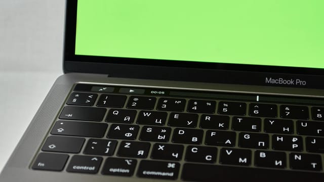 Russian keyboard MacBook Pro with a green screen. Modern electronic device.