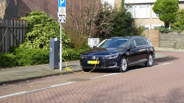 Electric car charging at a street station in Amsterdam, highlighting urban eco-friendliness.