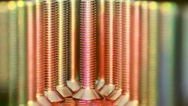 Vibrant close-up of metallic screws in rainbow hues, showcasing industry essentials.