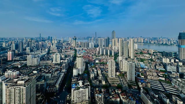 Expansive aerial view of Wuhan city skyline with modern skyscrapers and river in sight.