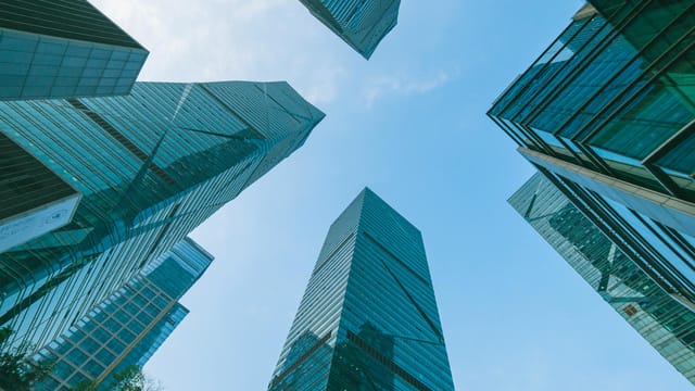 Low angle view of contemporary skyscrapers in Shenzhen, China under a clear blue sky.