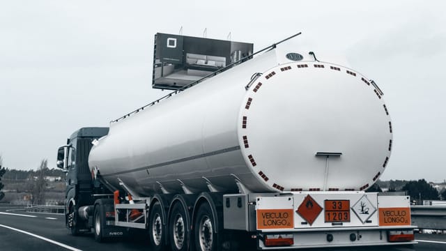 Rear view of a large tanker truck transporting fuel on a highway, emphasizing logistics and transportation.
