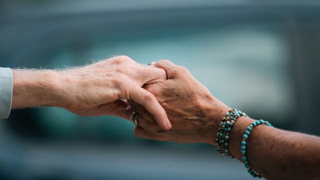 A heartfelt image of two elderly individuals holding hands, symbolizing love and support.