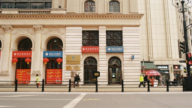 Street scene featuring classical architecture and pedestrians in an urban setting.