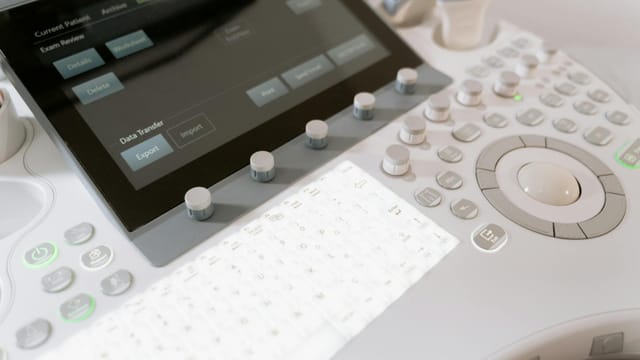 Detailed view of a medical ultrasound machine control panel with buttons and screen.