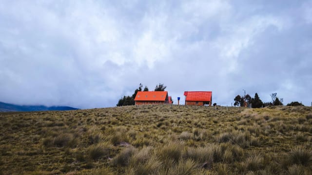 Rural homes with red roofs on a grassy hill under a cloudy sky in Berlin, Santander.